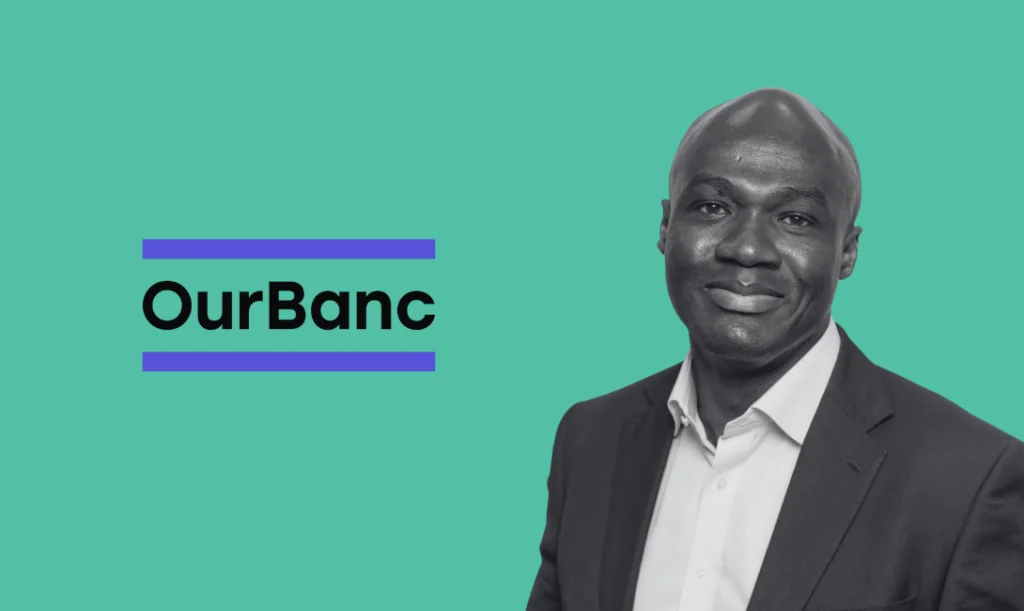 David Dwumah, founder of OurBanc Corporation, stands in front of the company's logo